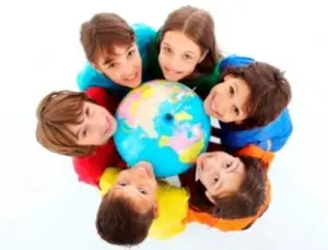 Kids holding together a terrestrial globe.